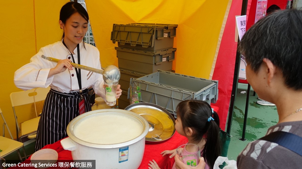 美食摊档负责人将饮料倒入可重用杯给活动参加者饮用